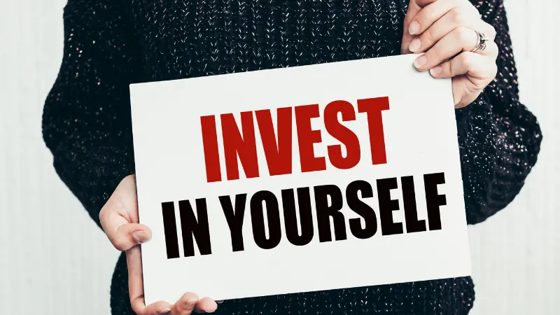 Une femme qui tient une pancarte mentionant Invest in Yourself