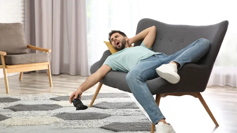 Homme entrain de se procrastiner sur son fauteuille