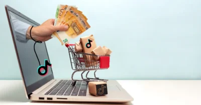 Concept de tiktok Business, une main qui sort d'un pc avec de l'argent, un chariot avec de la marchandise sur le pc (les achats)