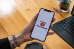 Une femme tient un smartphone et utlise l'application de vidéo YouTube