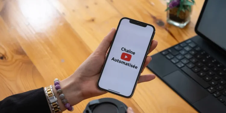 Une femme tient un smartphone et utlise l'application de vidéo YouTube
