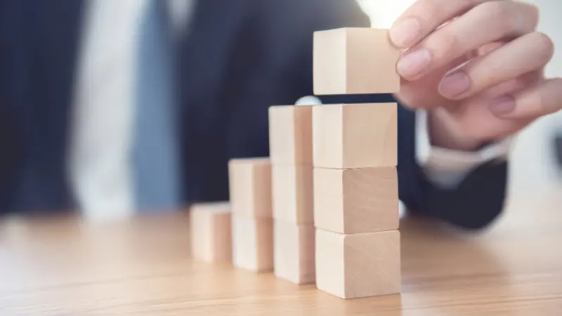 Gros plan d'une main d'homme d'affaire disposant des cubes de bois emplilés comme un escalier. Processus de réussite et de croissance d'un concept d'entrerpise