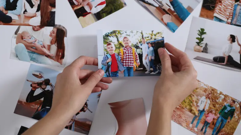 Des mains d'une femme entrain de créer sa vision Board avec différentes photos